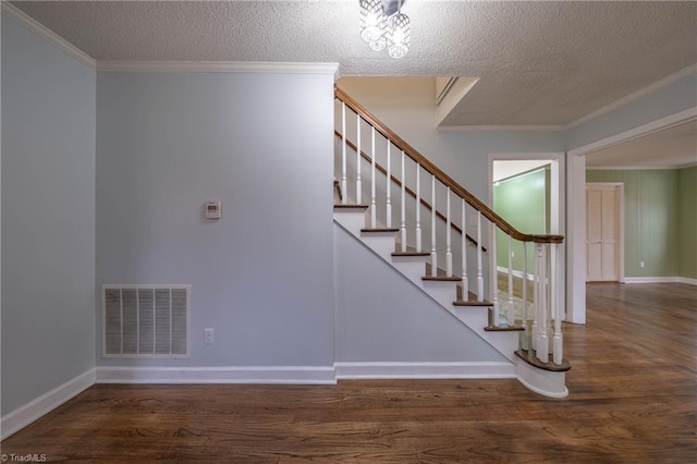 staircase with a textured ceiling, hardwood / wood-style flooring, and ornamental molding