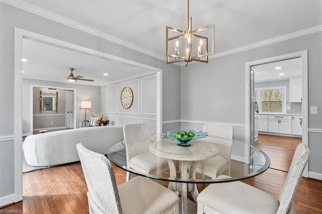 dining space featuring crown molding, wood finished floors, and ceiling fan with notable chandelier