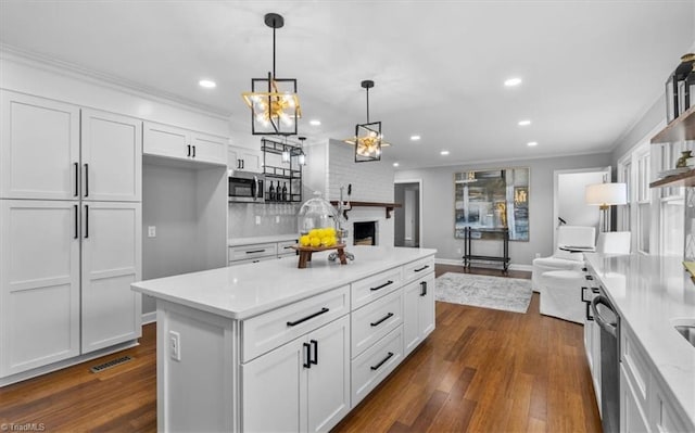 kitchen featuring stainless steel appliances, open floor plan, light countertops, and white cabinetry