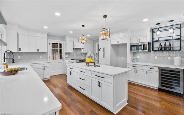 kitchen with beverage cooler, dark wood-style flooring, a sink, light countertops, and appliances with stainless steel finishes