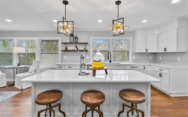 kitchen featuring light countertops, wood finished floors, a sink, and decorative backsplash