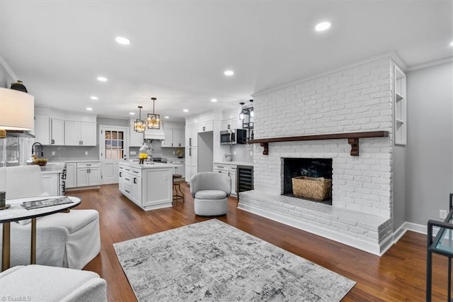 living area featuring recessed lighting, beverage cooler, baseboards, a brick fireplace, and dark wood-style floors