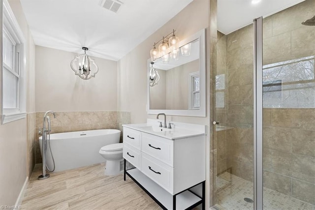 bathroom with a stall shower, visible vents, vanity, a freestanding tub, and a notable chandelier