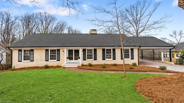 ranch-style house with a chimney, a front lawn, an attached carport, and brick siding