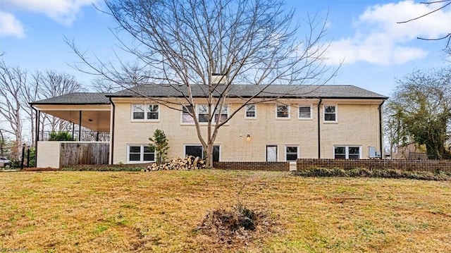 rear view of house with brick siding, a lawn, and fence