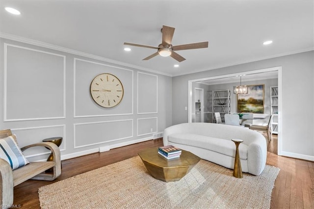 bedroom with recessed lighting, ceiling fan with notable chandelier, a decorative wall, wood finished floors, and ornamental molding