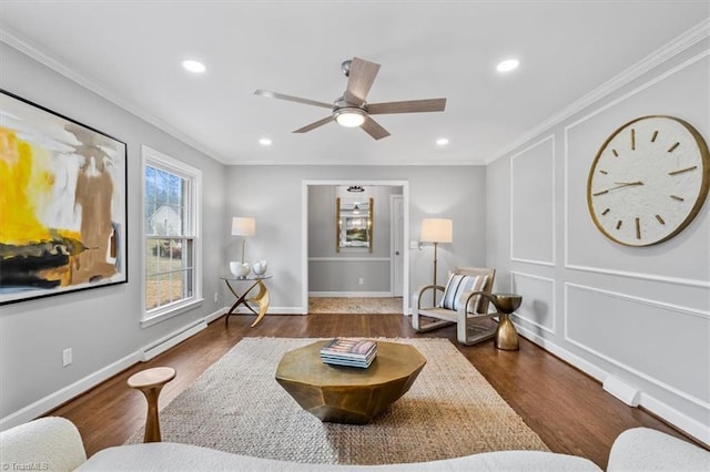 living area with recessed lighting, ornamental molding, a baseboard heating unit, wood finished floors, and baseboards