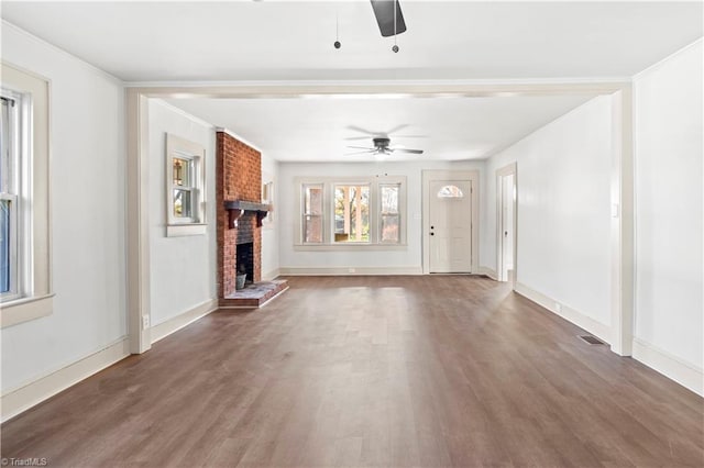 unfurnished living room with ceiling fan, dark hardwood / wood-style flooring, ornamental molding, and a fireplace