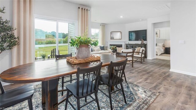 dining space with recessed lighting, a fireplace, wood finished floors, and baseboards