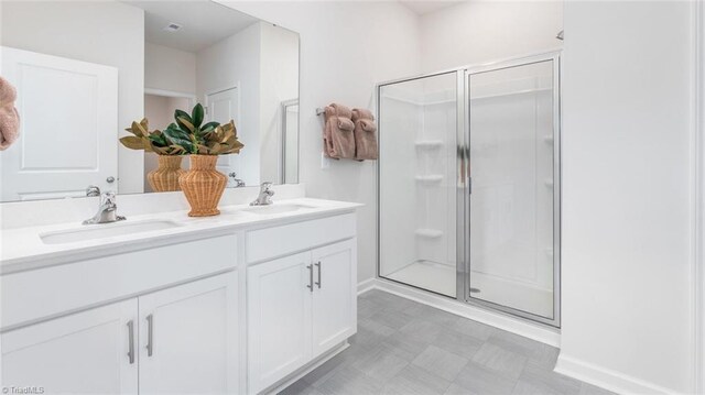 full bath with double vanity, a stall shower, a sink, and tile patterned floors
