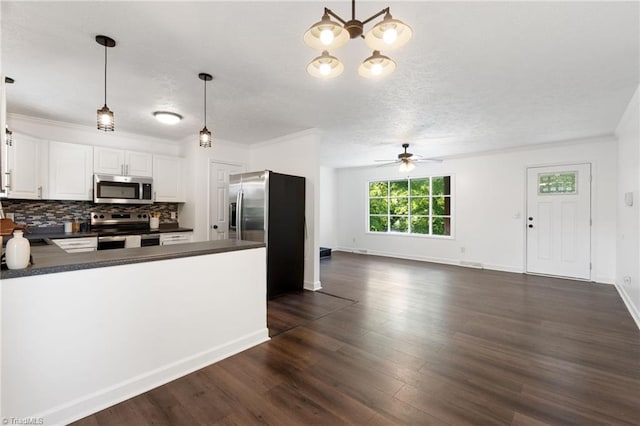 kitchen with stainless steel appliances, dark countertops, a ceiling fan, backsplash, and a peninsula