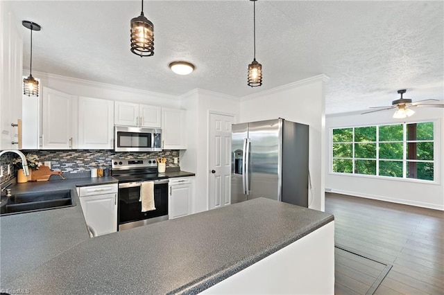 kitchen with stainless steel appliances, a sink, dark countertops, white cabinets, and tasteful backsplash