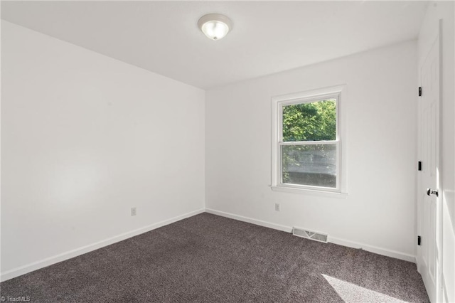 empty room with dark colored carpet and baseboards