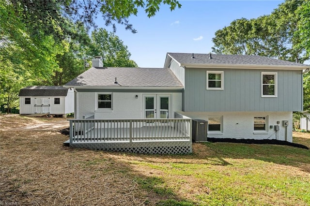rear view of property featuring a wooden deck, brick siding, a chimney, and a lawn