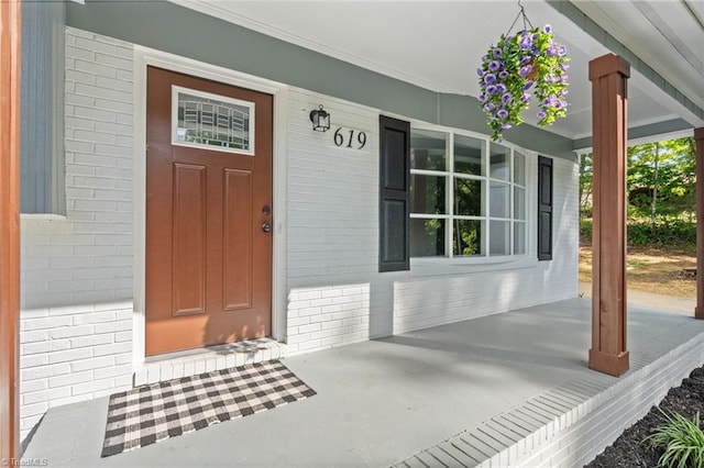 doorway to property featuring brick siding and covered porch
