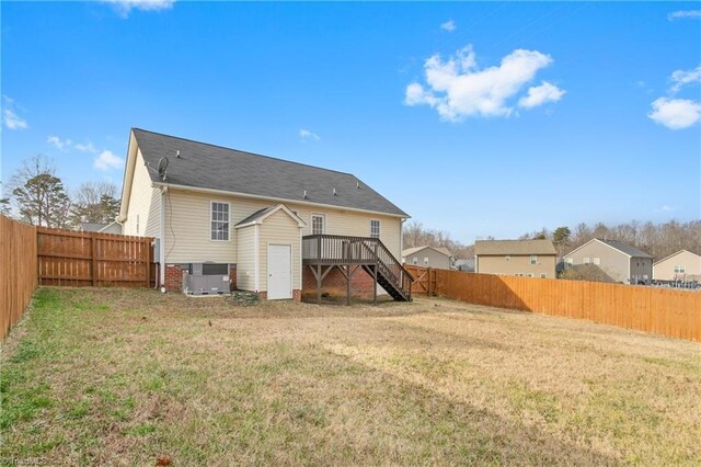 rear view of property with a deck, cooling unit, and a lawn