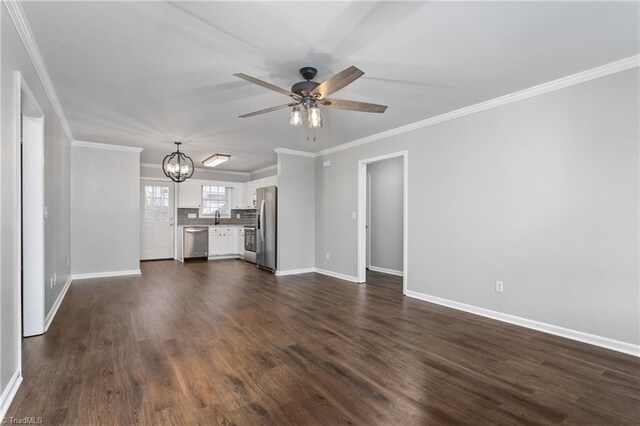 unfurnished living room with sink, dark wood-type flooring, ceiling fan with notable chandelier, and ornamental molding