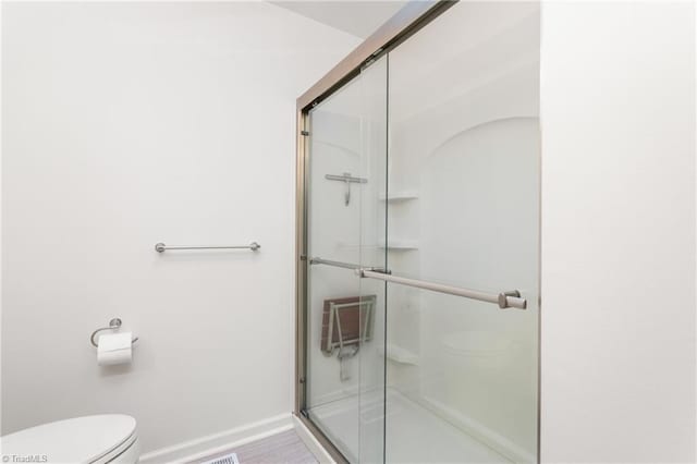 2909 Shamrock Dr, Greensboro, NC 27408 - bathroom with toilet, a stall shower, and baseboards