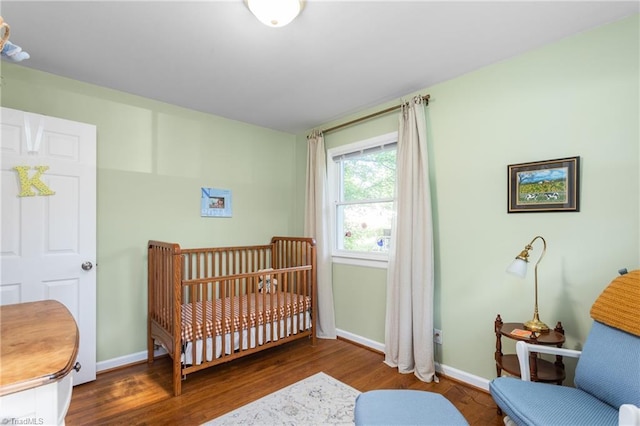 2909 Shamrock Dr, Greensboro, NC 27408 - bedroom featuring wood finished floors, baseboards, and a nursery area
