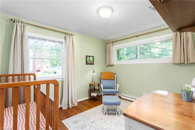 2909 Shamrock Dr, Greensboro, NC 27408 - bedroom featuring a baseboard heating unit, wood finished floors, multiple windows, and baseboards