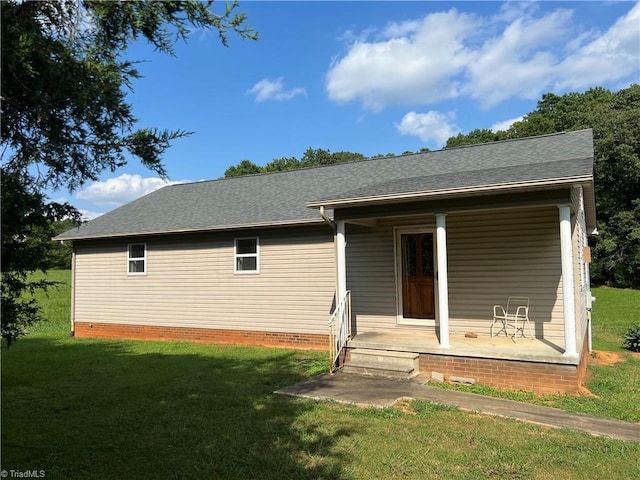 rear view of house with a shingled roof, a porch, and a lawn