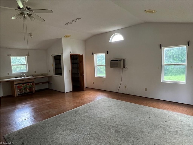 unfurnished living room with a wall unit AC, lofted ceiling, ceiling fan, a sink, and wood finished floors