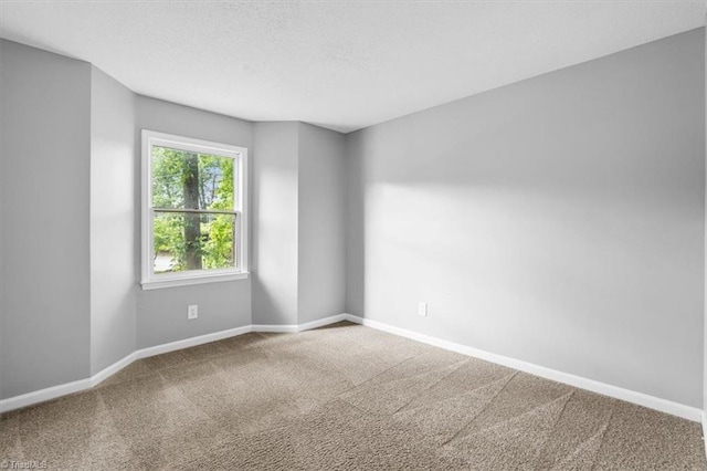 carpeted empty room featuring a textured ceiling and baseboards