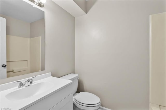bathroom featuring toilet, baseboards, and vanity