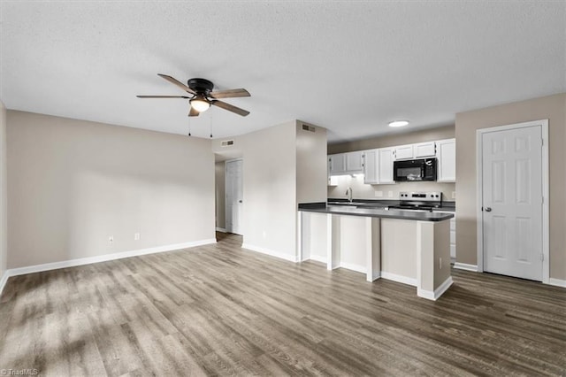 kitchen with dark wood-style flooring, electric range, black microwave, dark countertops, and a sink