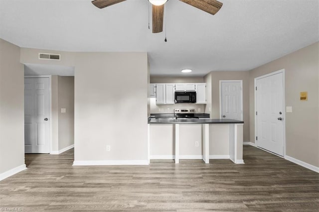 kitchen with black microwave, dark countertops, baseboards, and electric stove