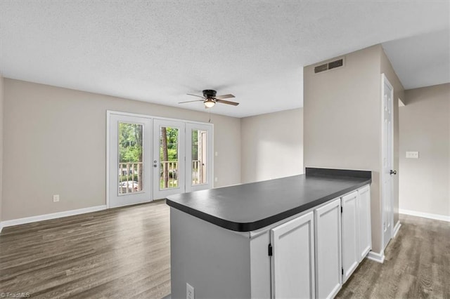kitchen featuring visible vents, dark wood-style flooring, dark countertops, baseboards, and ceiling fan