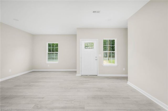 spare room featuring light wood-style flooring, baseboards, and visible vents