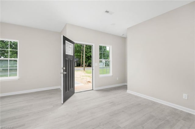 spare room featuring light wood-style flooring, a wealth of natural light, and baseboards