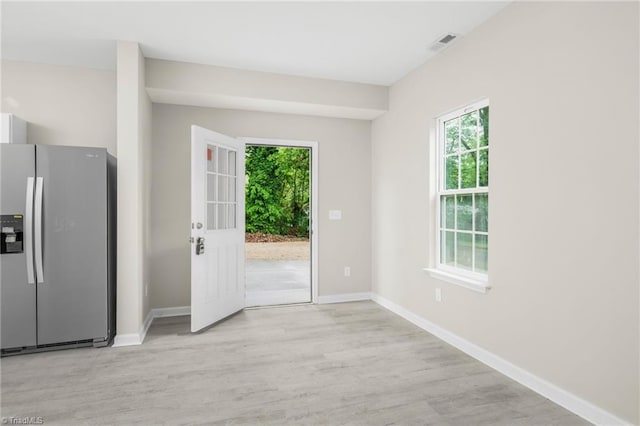 doorway featuring baseboards, light wood-type flooring, and visible vents