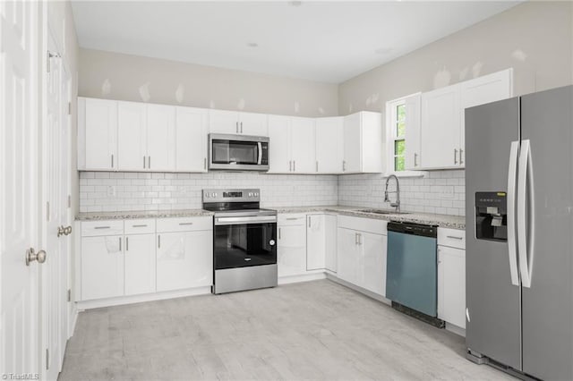 kitchen with a sink, white cabinetry, backsplash, and appliances with stainless steel finishes