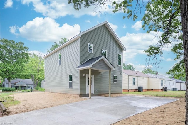 rear view of property featuring central air condition unit and driveway
