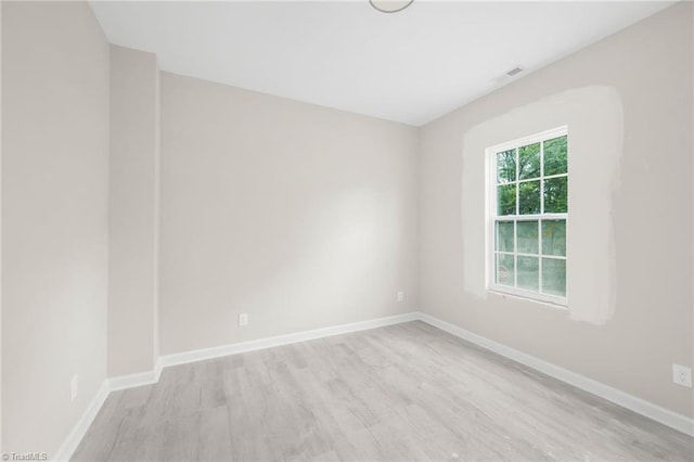 unfurnished room featuring visible vents, wood finished floors, and baseboards