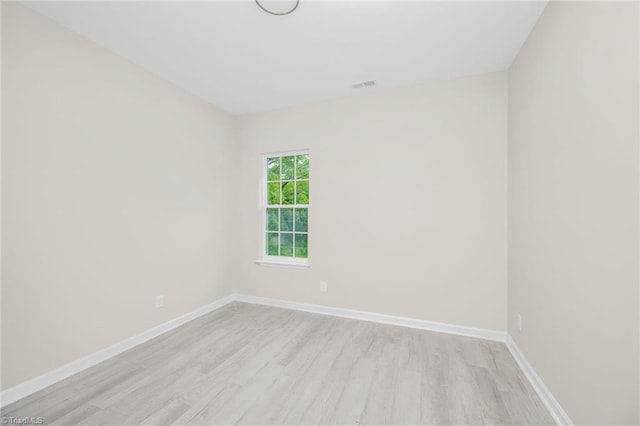 empty room with light wood-style flooring, baseboards, and visible vents