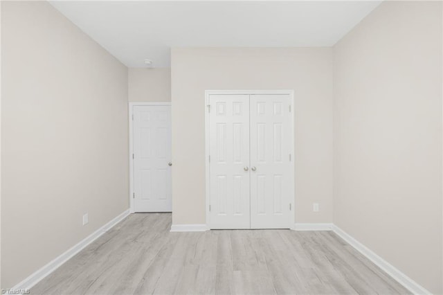 unfurnished bedroom with light wood finished floors, a closet, and baseboards