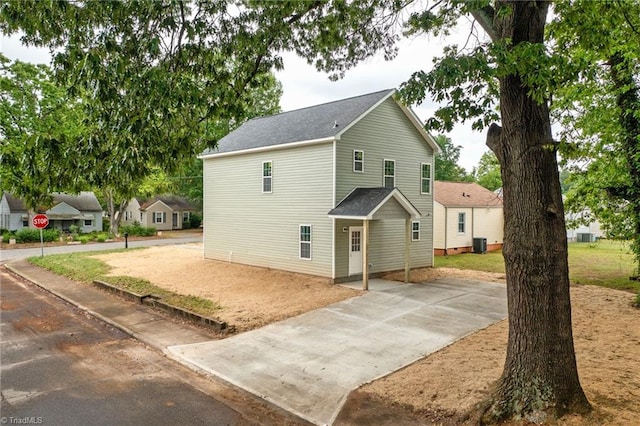 view of home's exterior with roof with shingles, cooling unit, and driveway