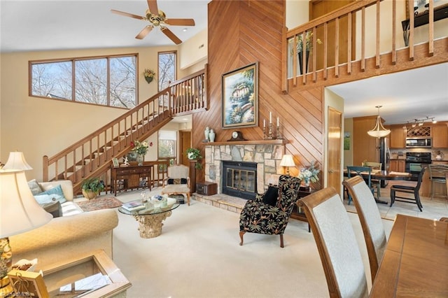 living room with stairway, a high ceiling, a fireplace, wood walls, and light carpet