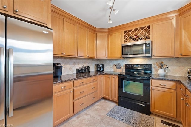 kitchen featuring light tile patterned floors, backsplash, appliances with stainless steel finishes, and dark stone counters