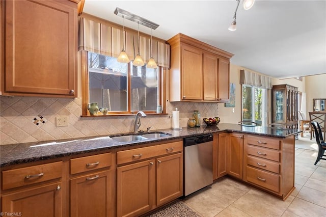 kitchen with brown cabinets, a sink, backsplash, stainless steel dishwasher, and a peninsula