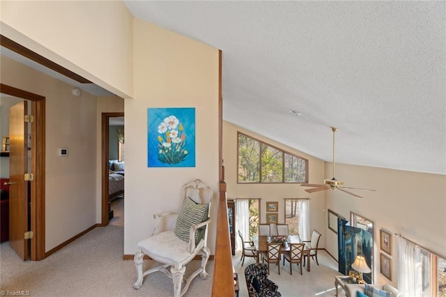 interior space with light carpet, high vaulted ceiling, a textured ceiling, baseboards, and ceiling fan