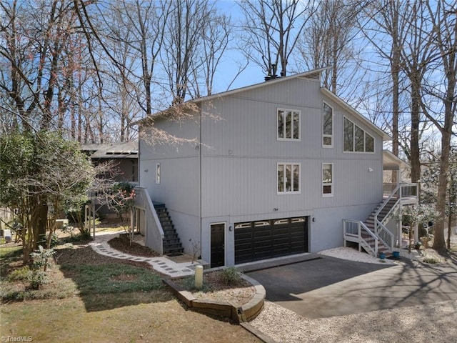 view of property exterior with aphalt driveway, stairway, and an attached garage