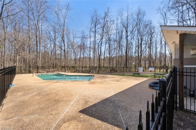 view of pool with a patio area, a fenced in pool, a view of trees, and fence