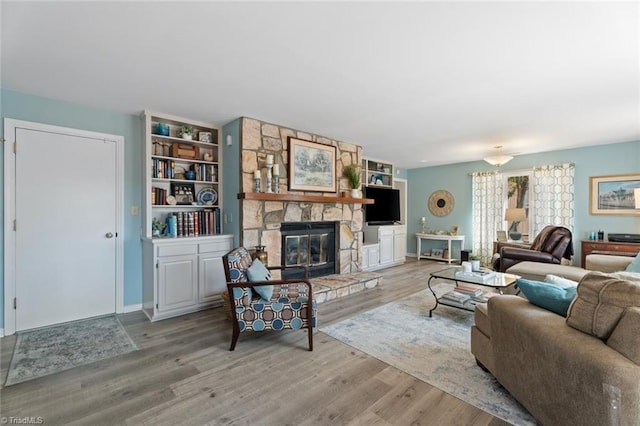 living room with a stone fireplace and wood finished floors