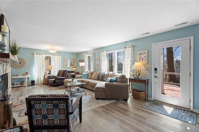 living room with visible vents, wood finished floors, and a glass covered fireplace