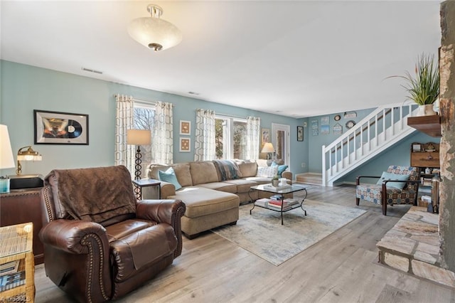 living area with stairway, wood finished floors, and visible vents