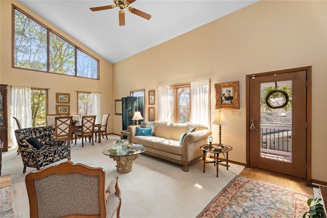 carpeted living room with ceiling fan, baseboards, and high vaulted ceiling